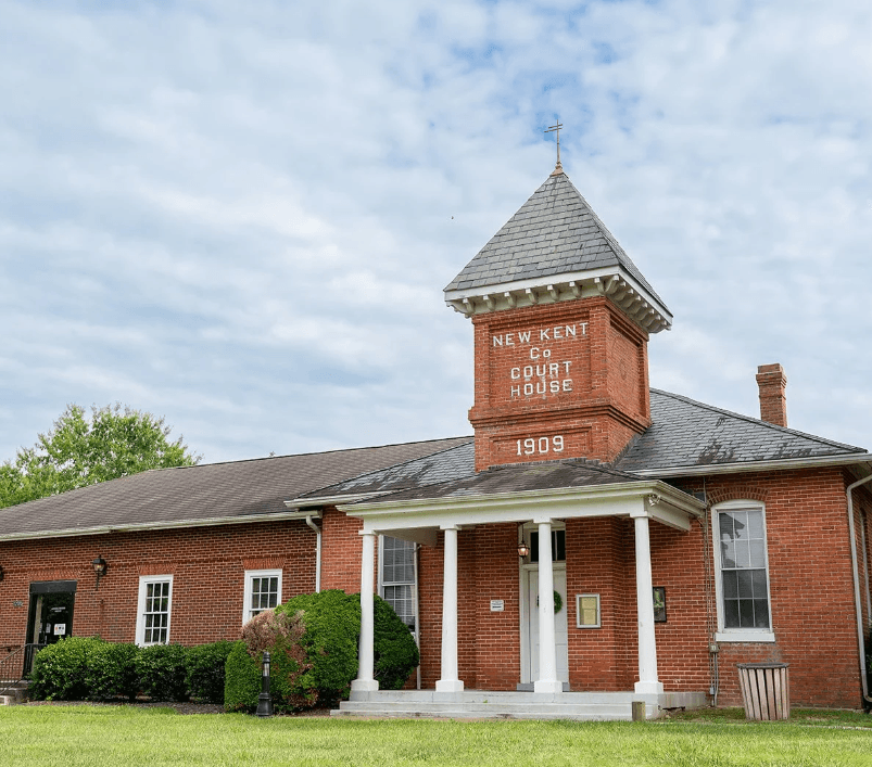 Red brick New Kent County Courthouse with white columns and a central tower, dated 1909.